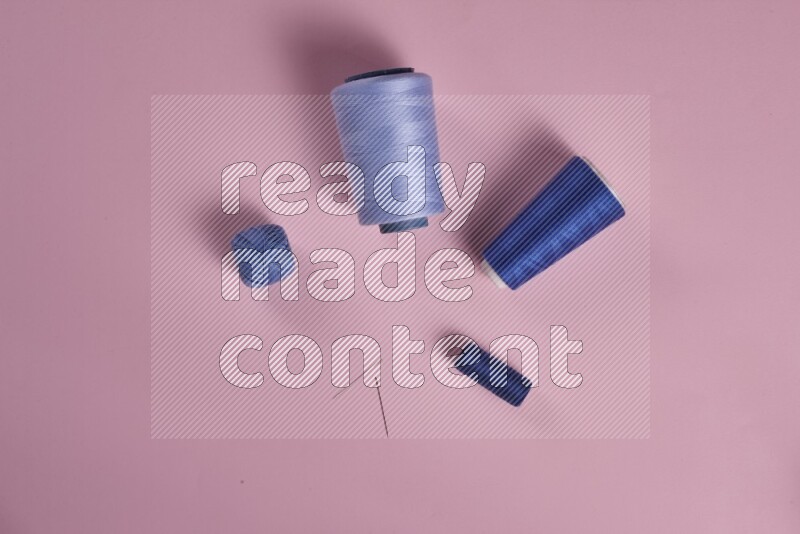 A blue collection of sewing and tailoring tools arranged on a pink background