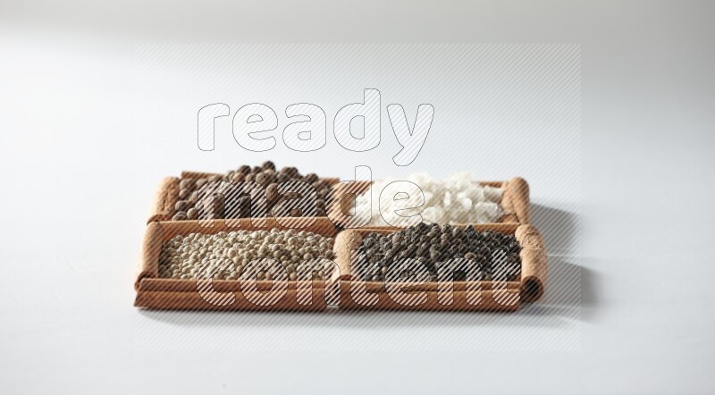 4 مربعات من أعواد القرفة ممتلئة ببهار الفلفل الحلو والملح الأبيض والفلفل الأبيض والفلفل الأسود على أرضية بيضاء