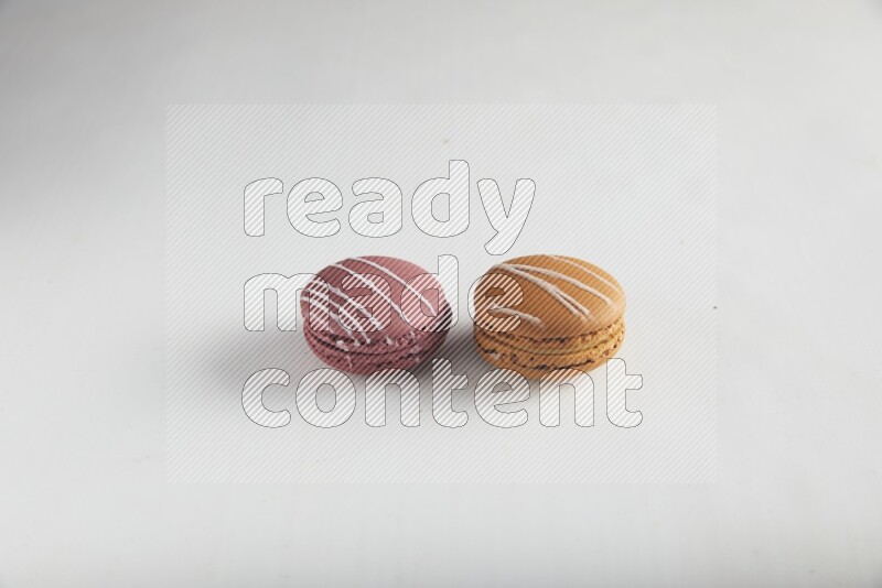 45º Shot of of two assorted Brown Irish Cream, and Red Poppy Flower macarons on white background