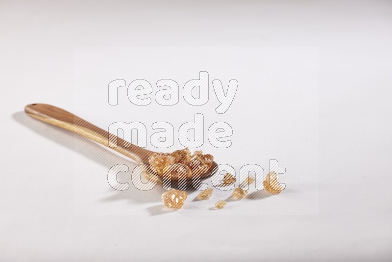 A wooden ladle filled with gum arabic on white flooring