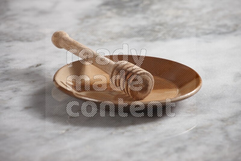 Multicolored pottery plate with wooden honey dipper in it on grey marble background