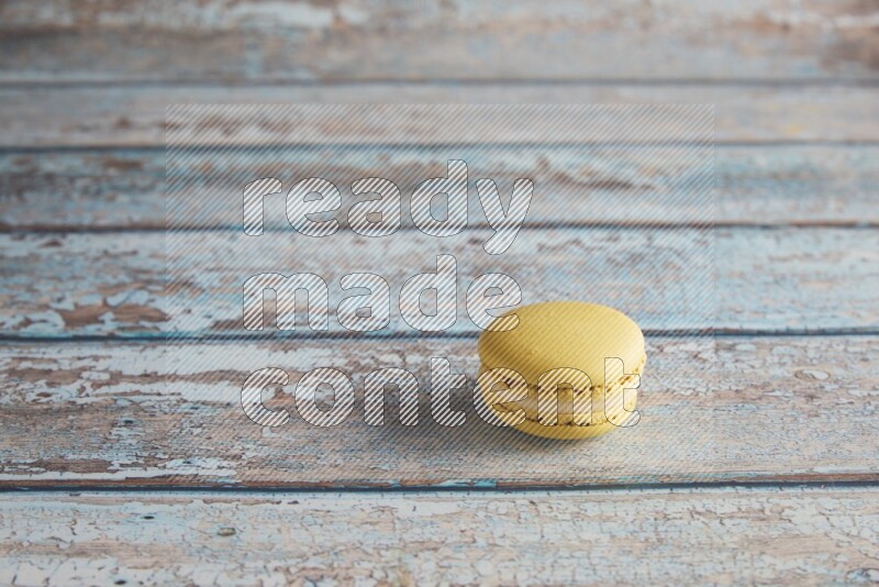 45º Shot of Yellow Lime macaron on light blue wooden background