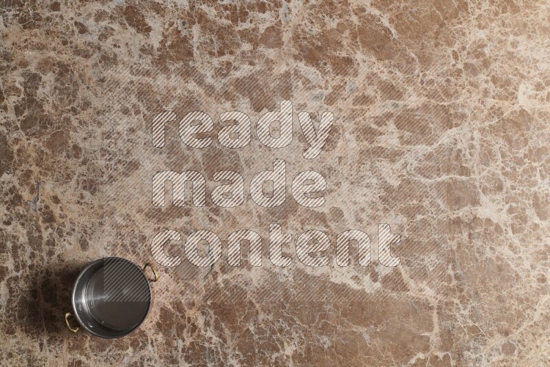 A small copper pot on beige marble background