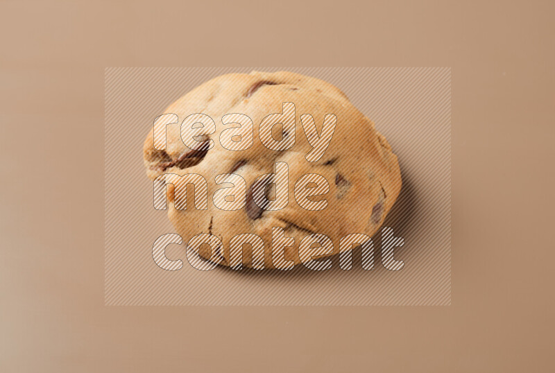 a whole chocolate chip cookie on a brown background