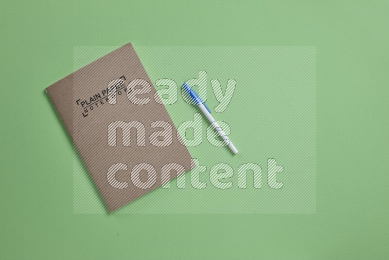 A notebook with different school supplies on green background