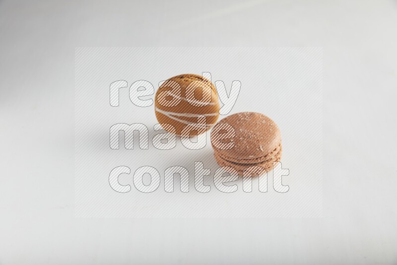 45º Shot of of two assorted Brown Irish Cream, and Brown Hazelnuts macarons on white background