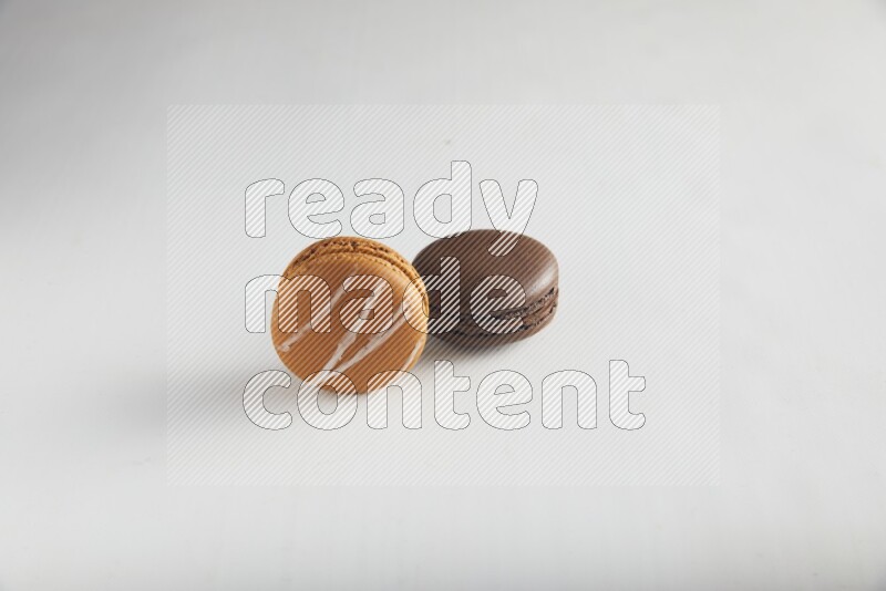 45º Shot of of two assorted Brown Irish Cream, and Brown Dark Chocolate macarons on white background