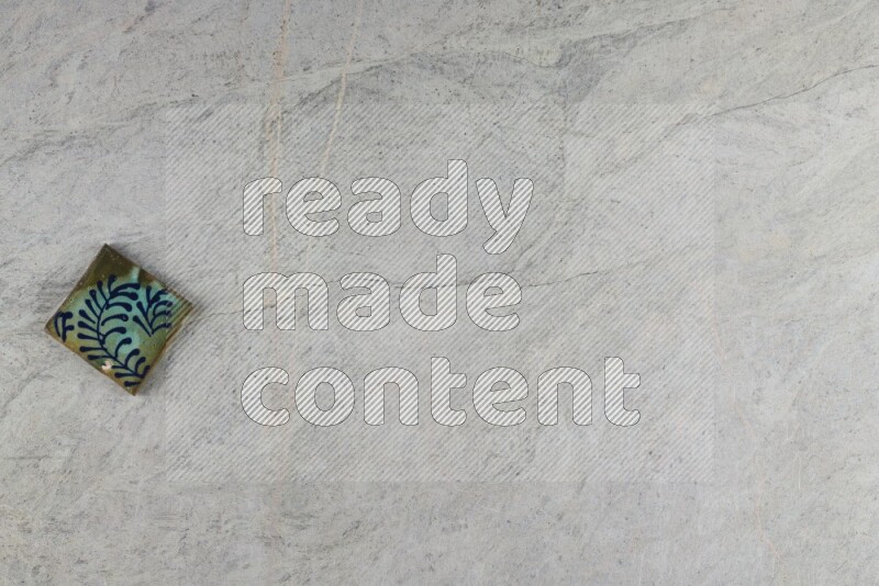 A decorative pottery coaster on grey marble background