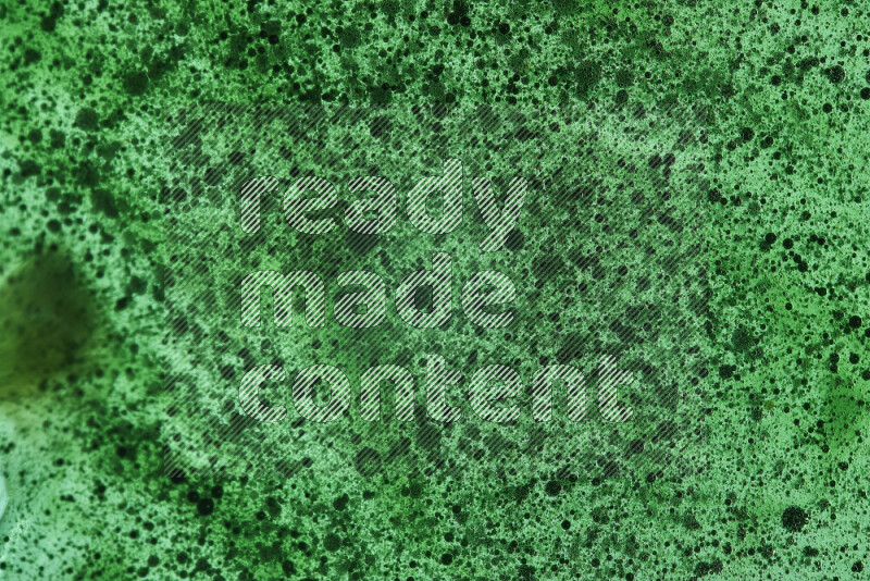 Close-ups of abstract green watercolor drops on oil Surface on green background