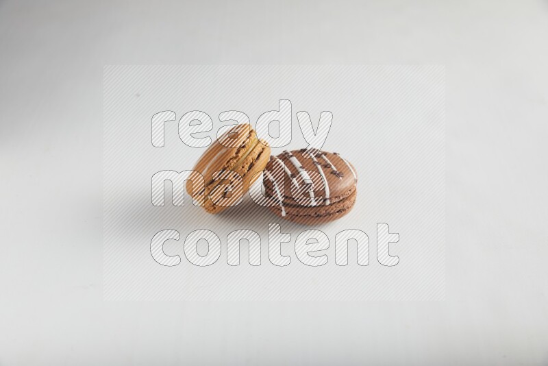 45º Shot of of two assorted Brown Irish Cream, and Brown white Chocolate Caramel macarons on white background