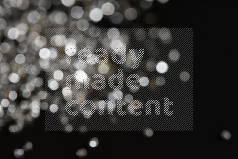 Silver shimmering fragments of glass scattered on a black background