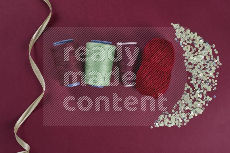 مجموعة من أدوات الخياطة والتفصيل خضراء وحمراء اللون على خلفية حمراء