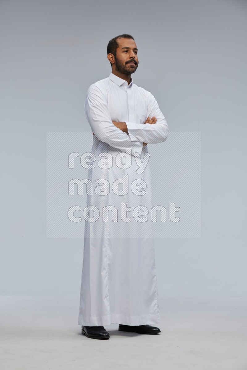 Saudi man wearing Thob standing with crossed arms on Gray background