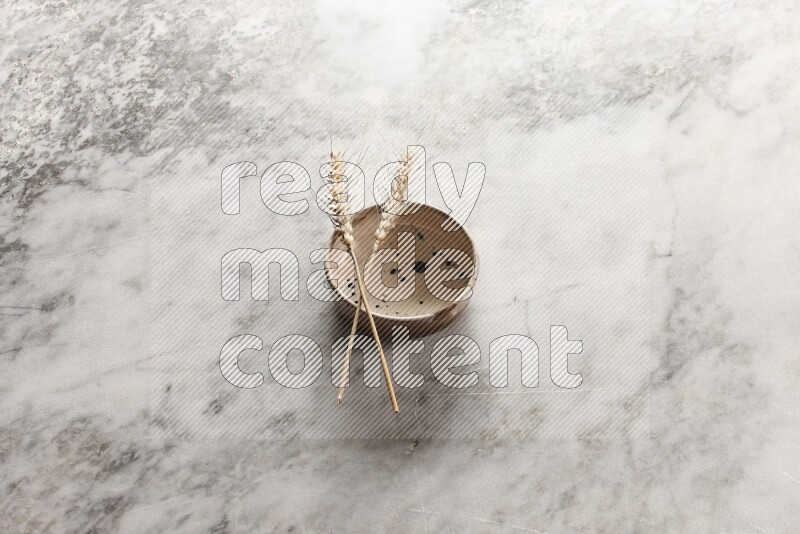 سنابل من القمح علي وعاء فخاري متعدد الألوان علي خلفية من الرخام الرمادي