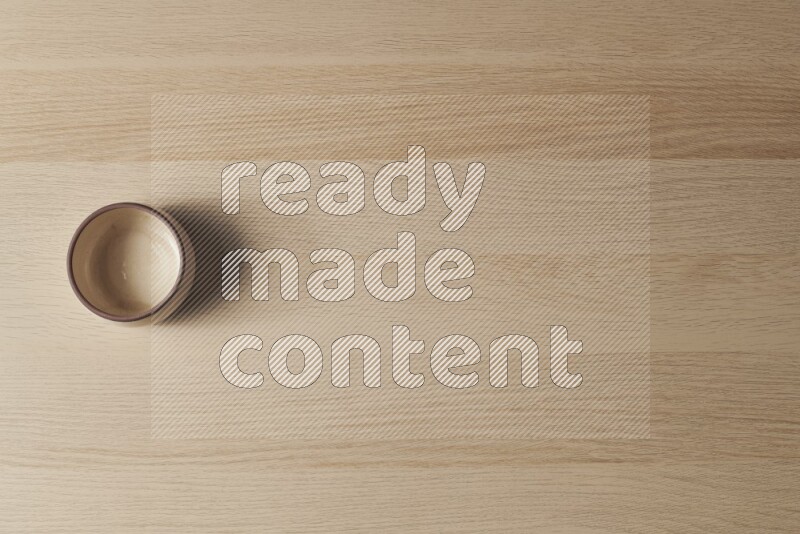 A beige pottery oven bowl on light wooden background