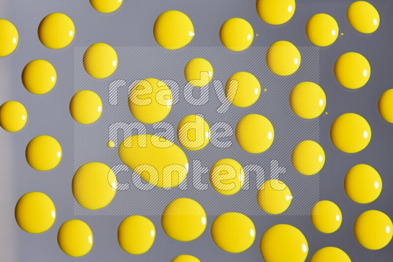 Close-ups of abstract yellow paint droplets on grey background