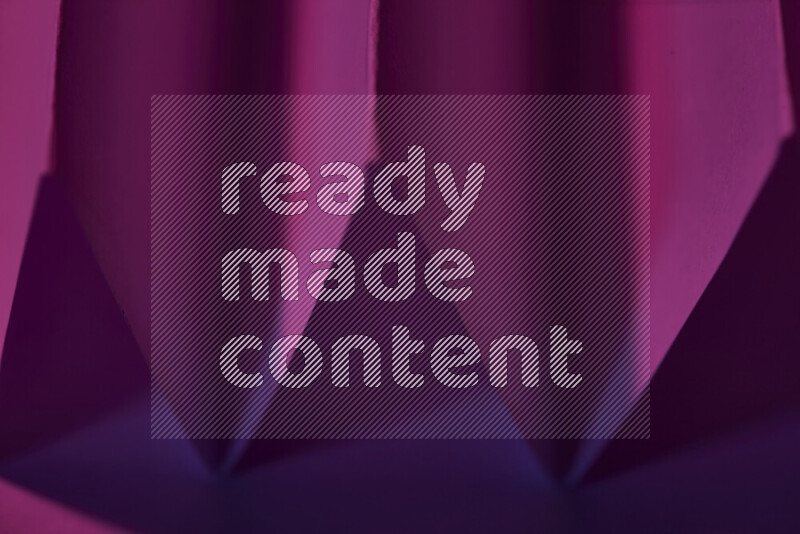 صورة مجردة مقربة تظهر طيات ورقية هندسية حادة بتدرجات اللون الارجواني