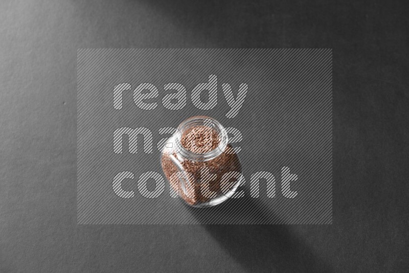 A glass spice jar full of flax on black flooring