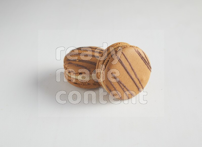 45º Shot of two light brown  Almond Cream macarons on white background