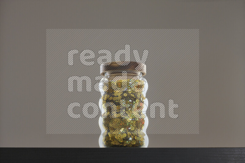 Sequins in a glass jar on black background