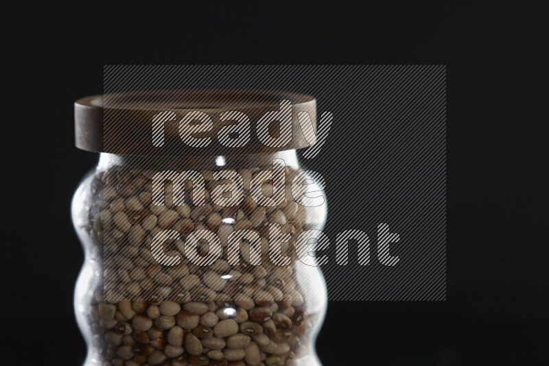 Black-eyed peas in a glass jar on black background