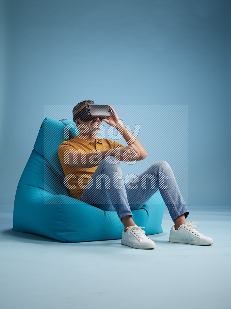 A man sitting on a blue beanbag and gaming with VR