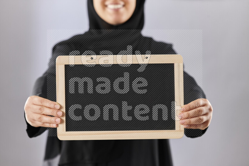A woman in abaya holding books and a board in different positions (back to school)