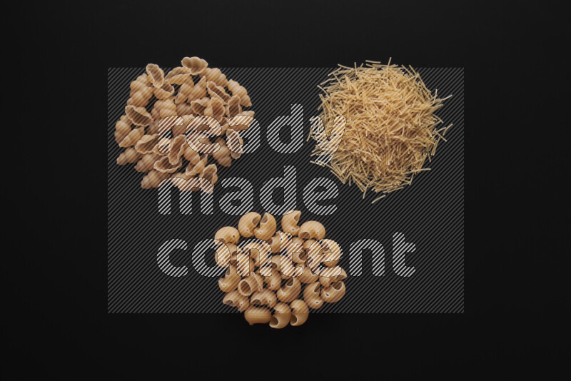 Different pasta types in bunches on black background