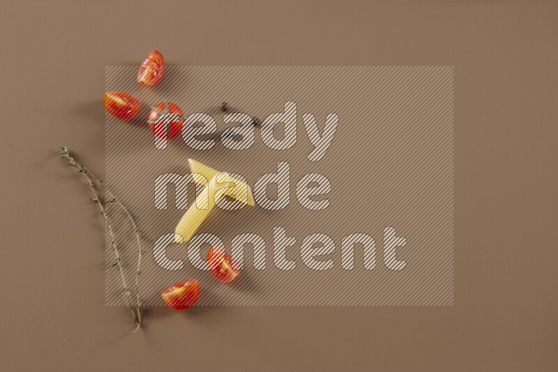Raw pasta with different ingredients such as cherry tomatoes, garlic, onions, red chilis, black pepper, white pepper, bay laurel leaves, rosemary and cardamom on beige background