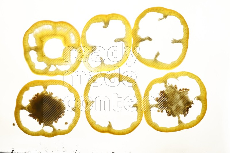 Yellow bell pepper slices on illuminated white background