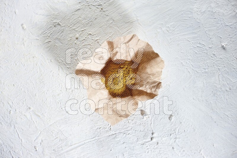 Turmeric powder in a crumpled piece of paper on textured white flooring