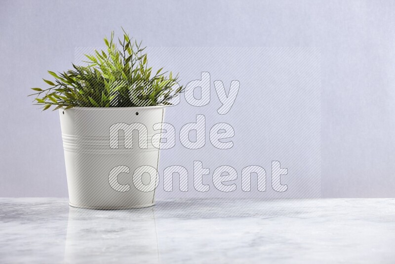 Green artificial plant in white pot on grey marble background