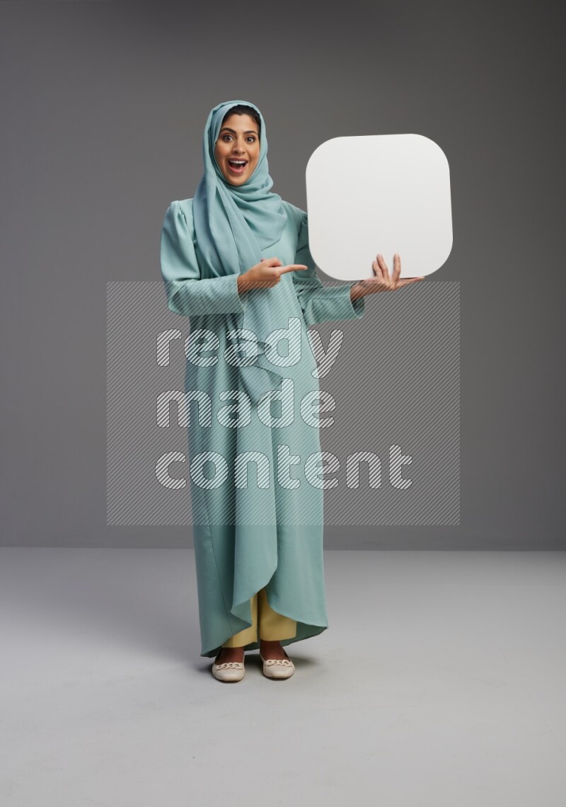 Saudi Woman wearing Abaya standing holding social media sign on Gray background