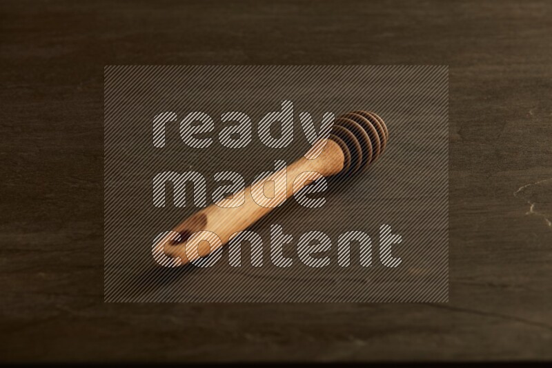 Wooden honey dipper on black slate background