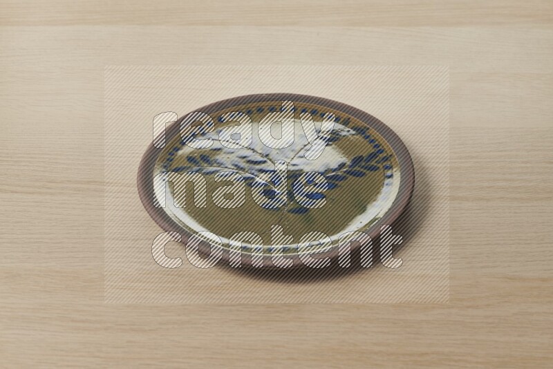 A decorative pottery plate on light wooden background