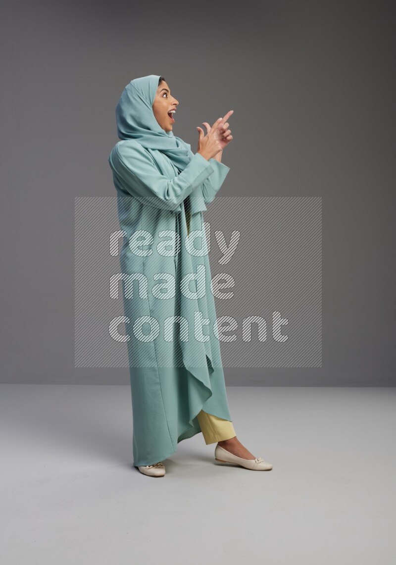 Saudi Woman wearing Abaya standing interacting with the camera on Gray background