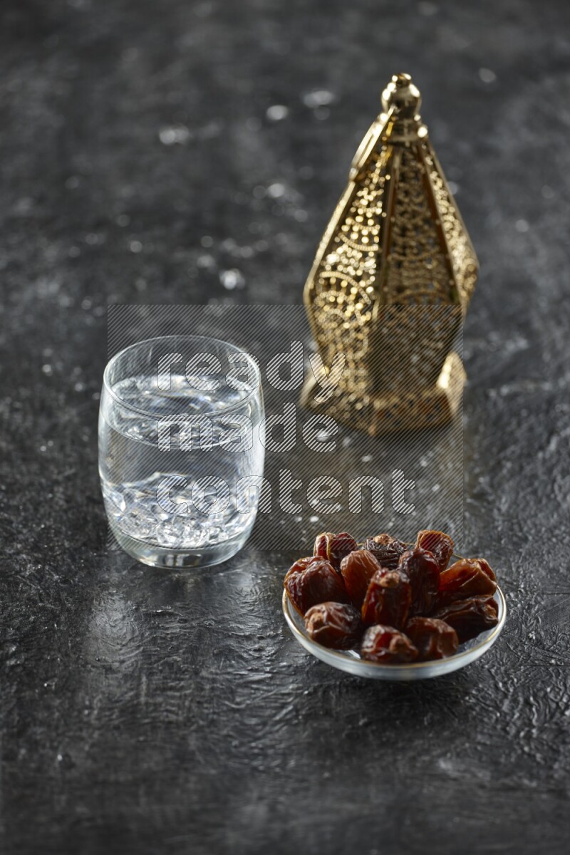 A golden lantern with different drinks, dates, nuts, prayer beads and quran on textured black background