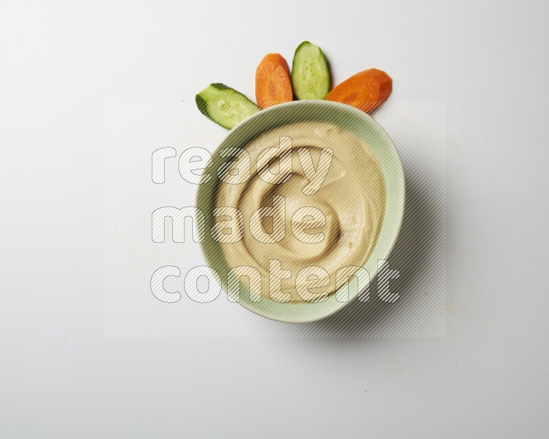 plain Hummus in a green plate on a white background