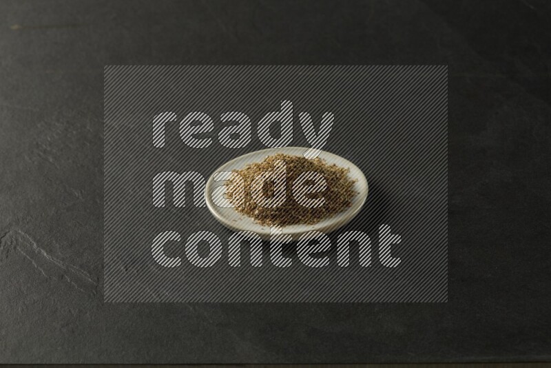 white ceramic round sauce dish filled with herbs on grey textured countertop