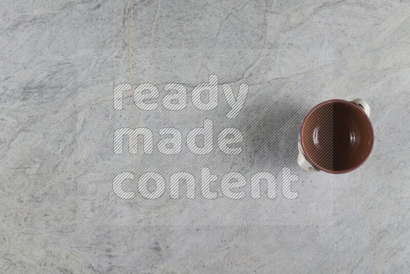 A multicolored pottery pot with its lid on grey marble background
