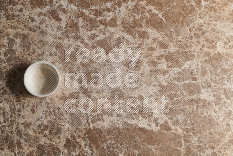 A pottery cup on beige marble background