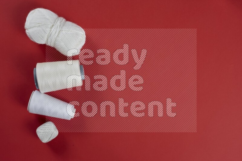 A white collection of sewing and tailoring tools arranged on a red background