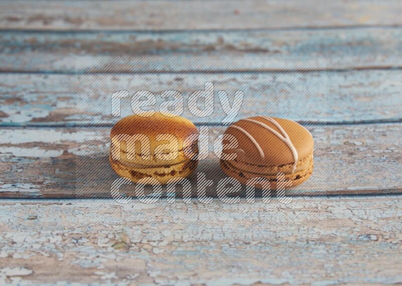 45º Shot of of two assorted Brown Irish Cream, and Yellow Crème Brulée macarons on light blue background