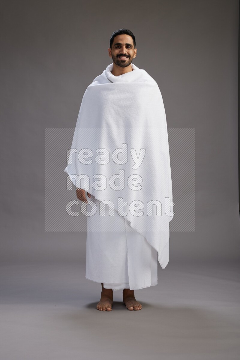 A man wearing Ehram Standing Interacting with the camera on gray background