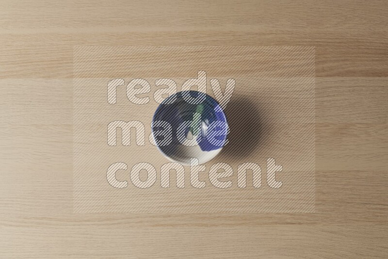 A multicolored pottery bowl on light wooden background