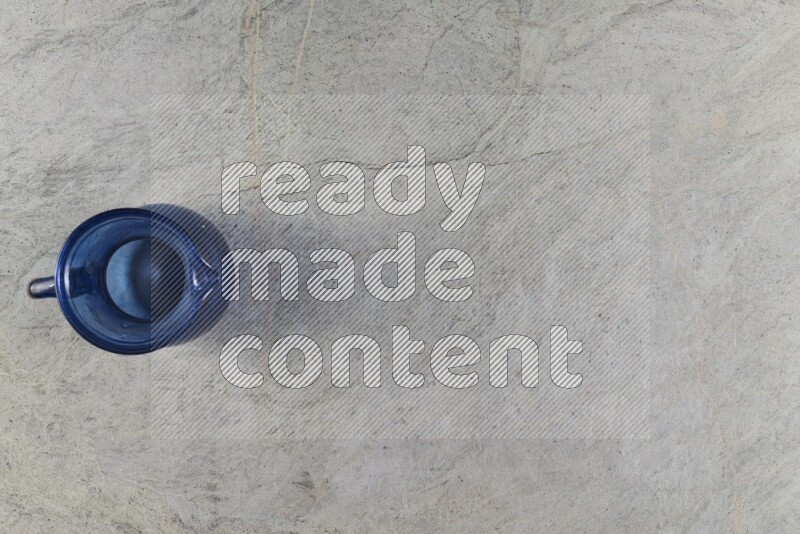 A colored glass jug on grey marble background