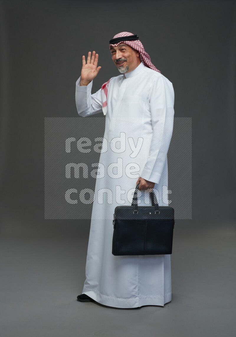 Saudi man with shomag Standing holding bag on gray background