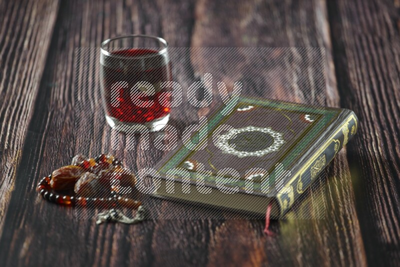 Quran with dates, prayer beads and different drinks all placed on wooden background