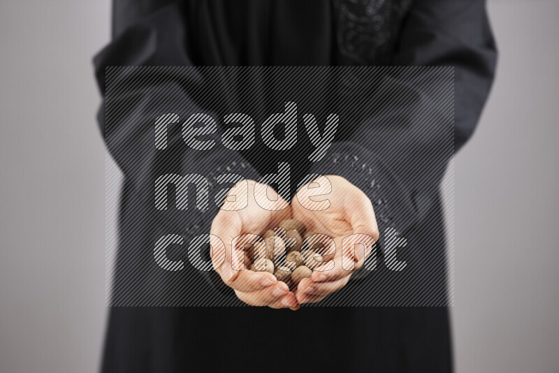 Woman in abaya holding different kinds of spices in different positions