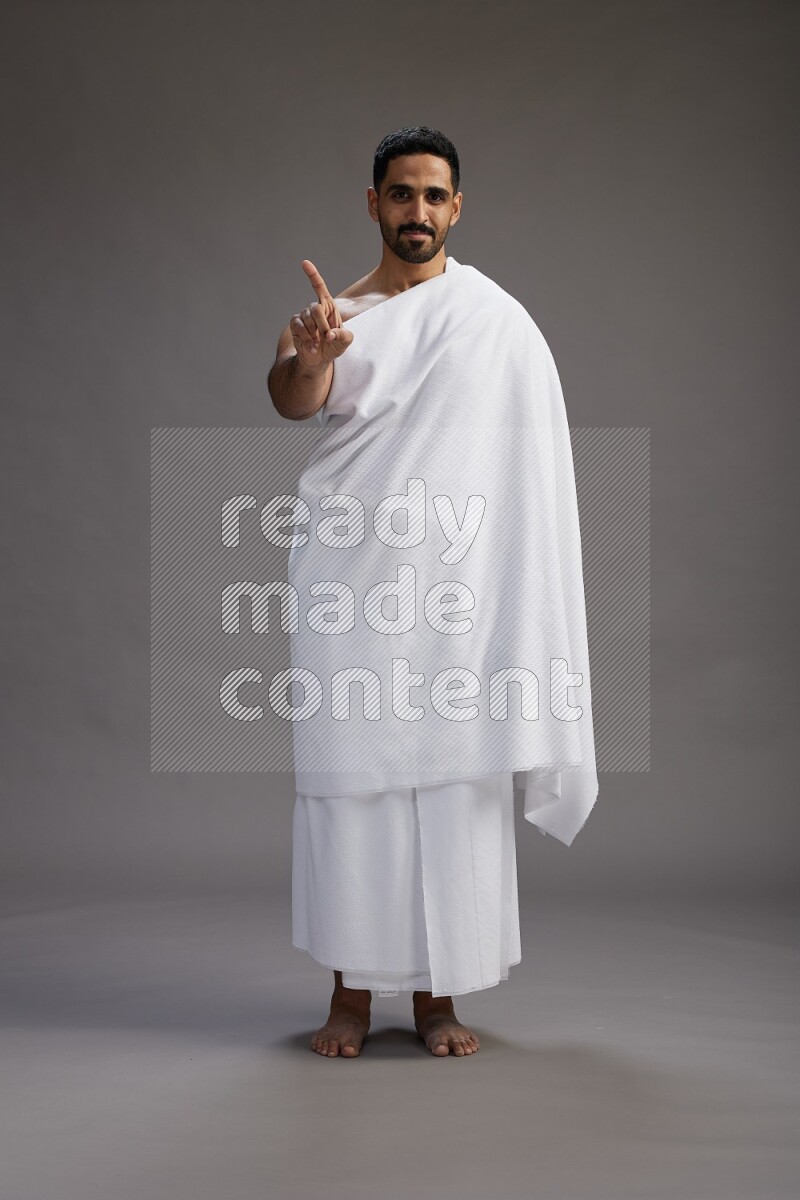 A man wearing Ehram Standing Interacting with the camera on gray background